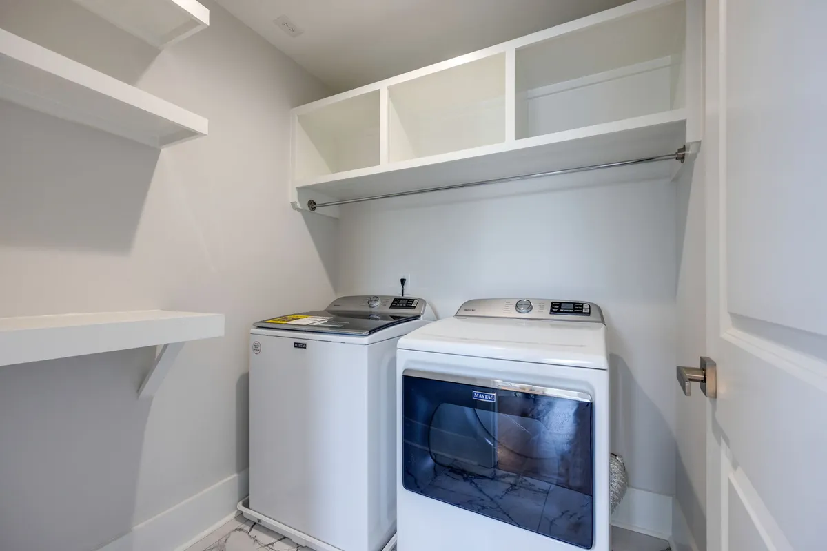 A practical laundry area with a washing machine, dryer, and well-organized shelves, emphasizing convenience and efficiency for guests during their stay.