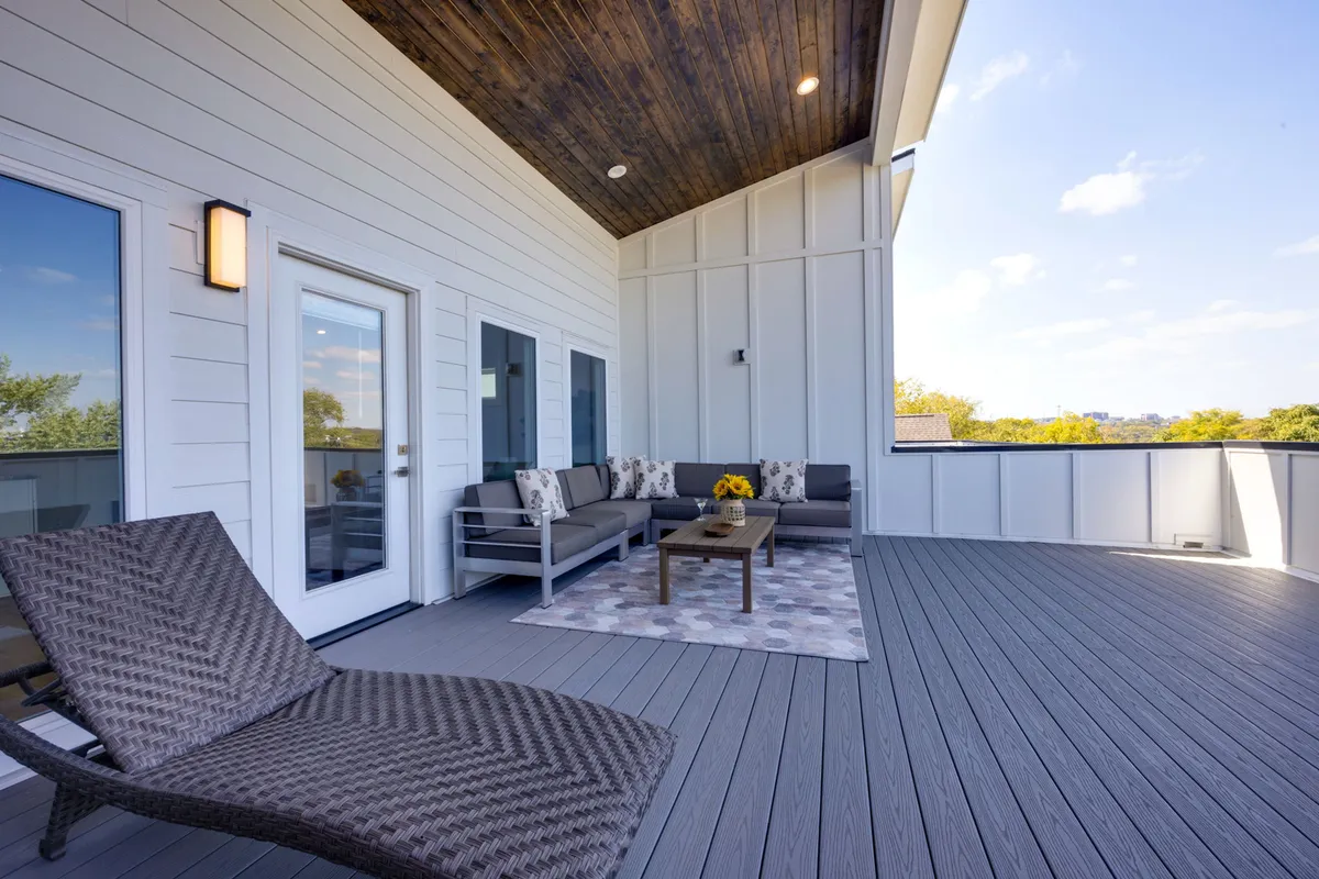 A comfortable outdoor seating area with a coffee table, decorative rug, and vibrant sunflower arrangement. The space is styled for relaxation or hosting, ideal for morning coffee, evening chats, or small gatherings.