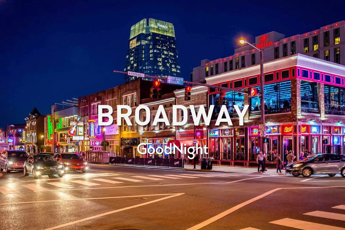 A lively Nashville city street at night, featuring neon signs, bustling traffic lights, illuminated buildings, and people walking along the sidewalks. The scene is vibrant and energetic, capturing the essence of Nashville's nightlife and entertainment districts.