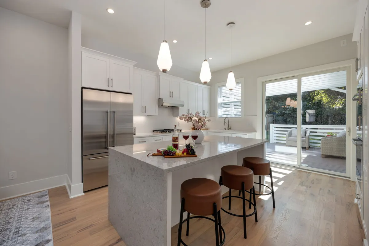A spacious kitchen island with stools is the focal point in this image, complemented by a window view in the background. The layout encourages socializing, with space for meal prep and casual dining, making it ideal for group gatherings or breakfast chats.